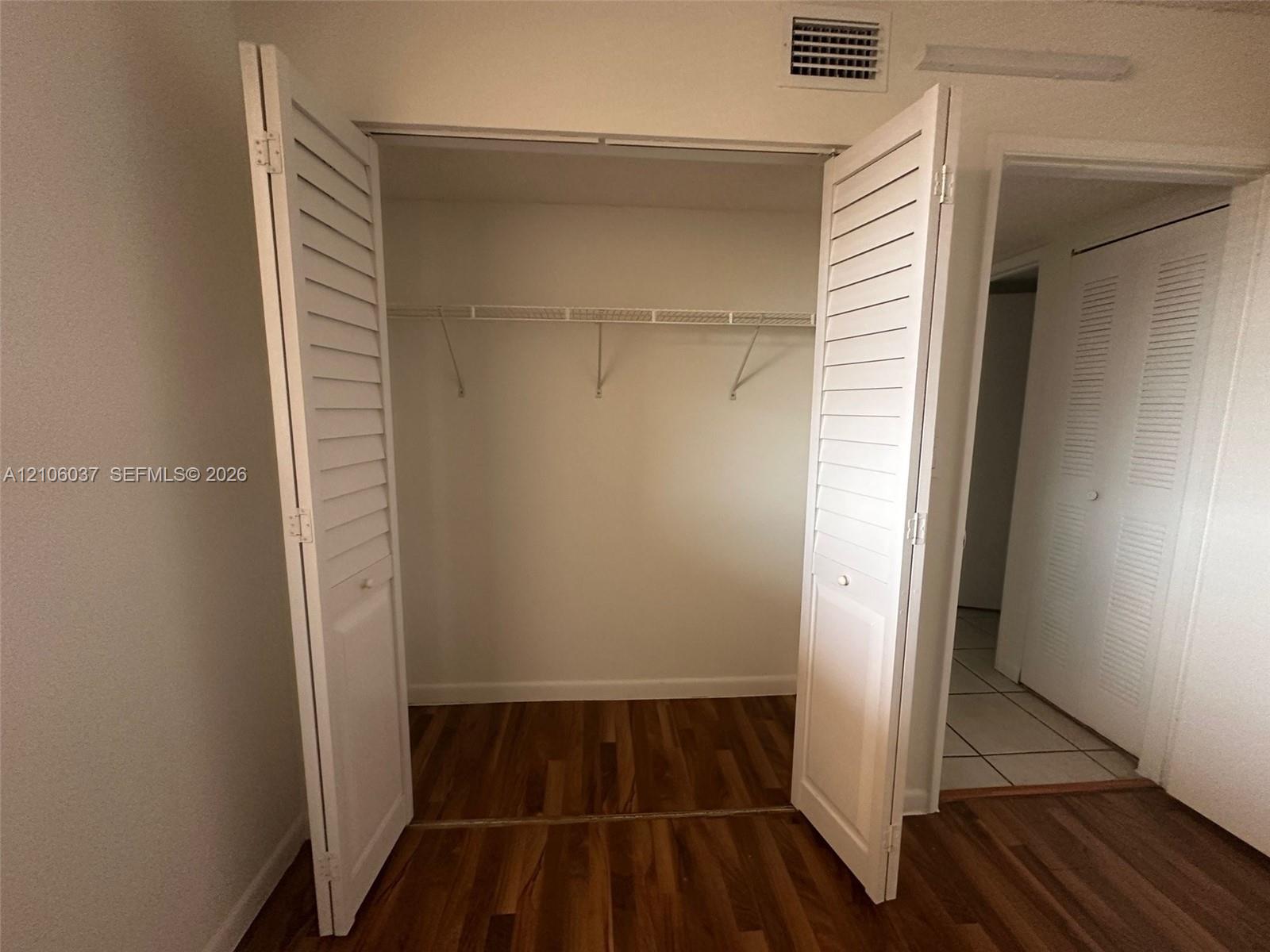 Closet featuring white louvered bifold doors, wood-finish flooring, and integrated wire shelving