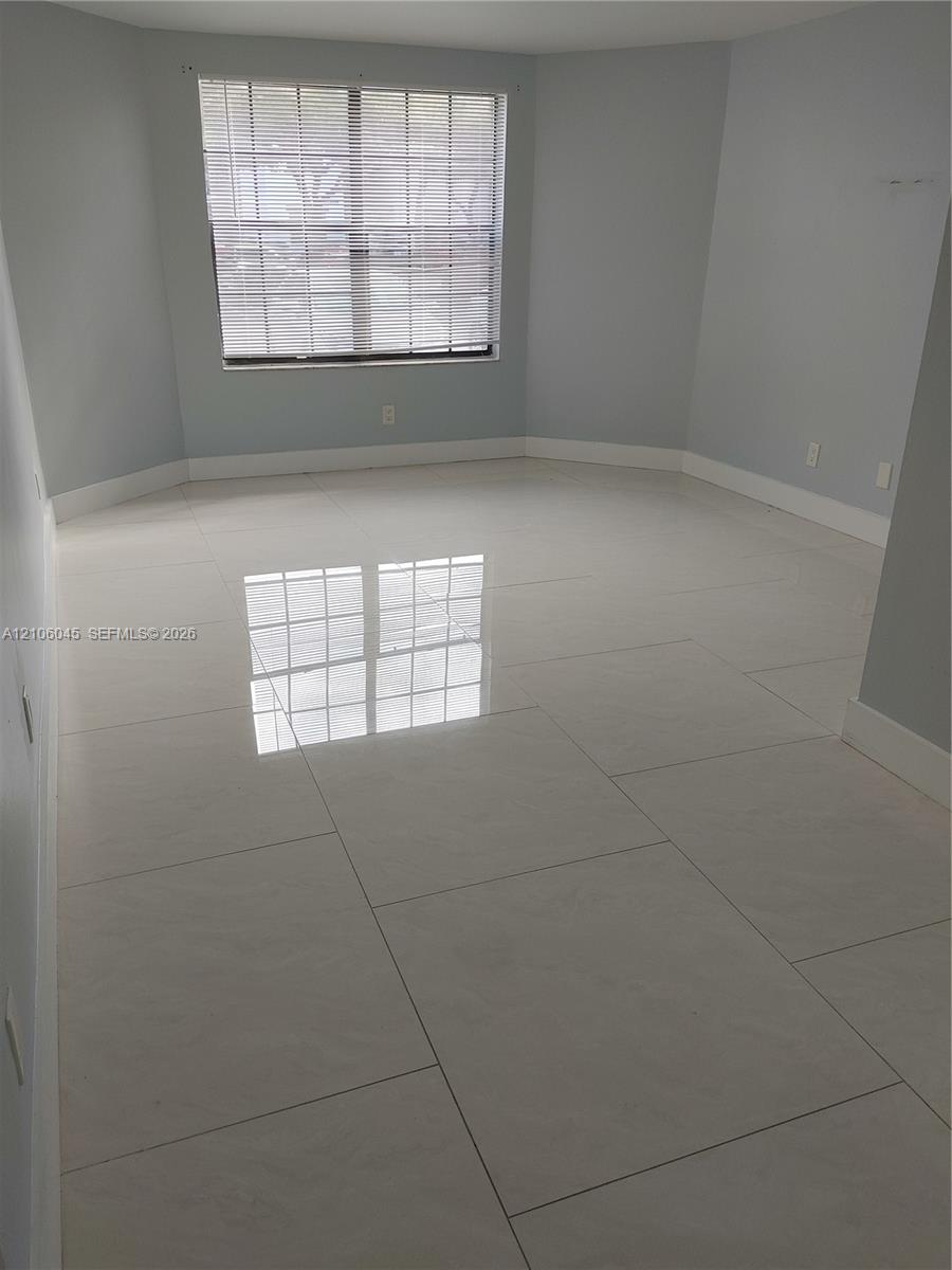 Neutral-toned room featuring large-format polished tile flooring and a multi-pane window