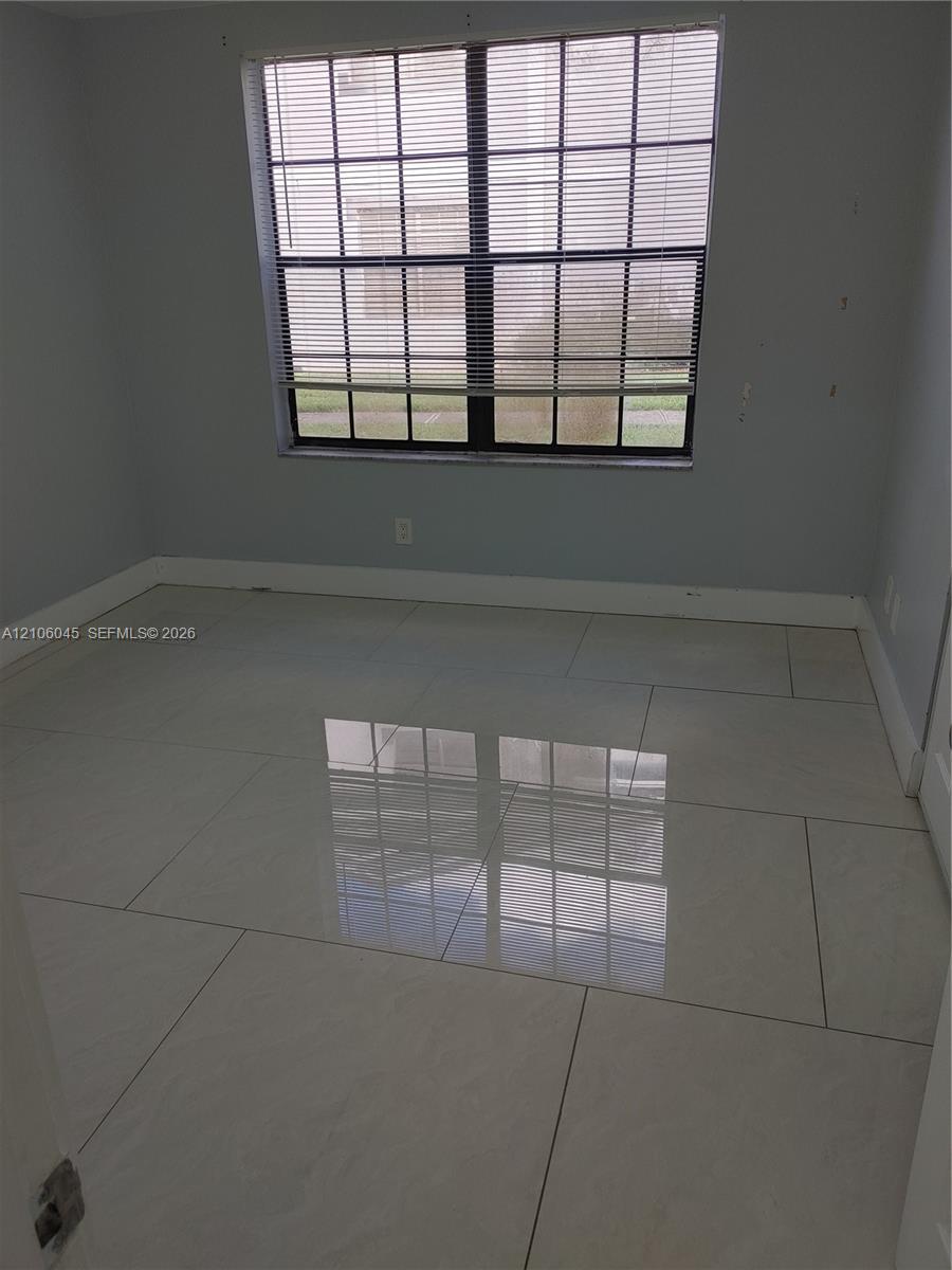 Large-format polished tile flooring, neutral wall tones, and a multi-pane window featuring integrated window blinds