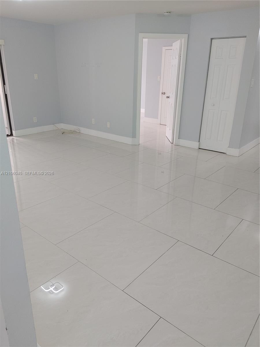 Large-format white tile flooring, neutral wall tones, and two-panel interior doors