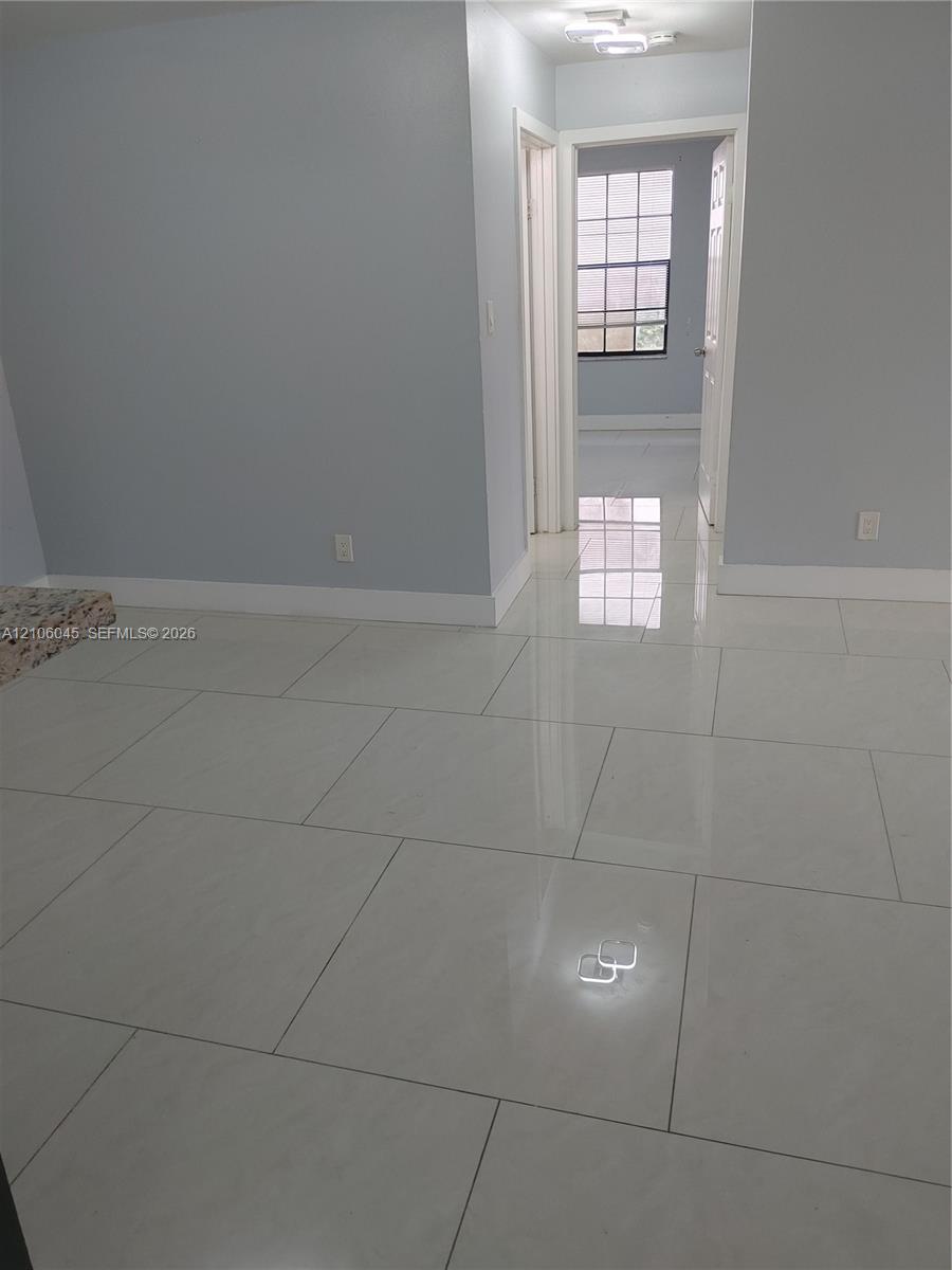 Large-format polished ceramic tile flooring, neutral wall tones, multi-pane window, and flush-mount overhead lighting