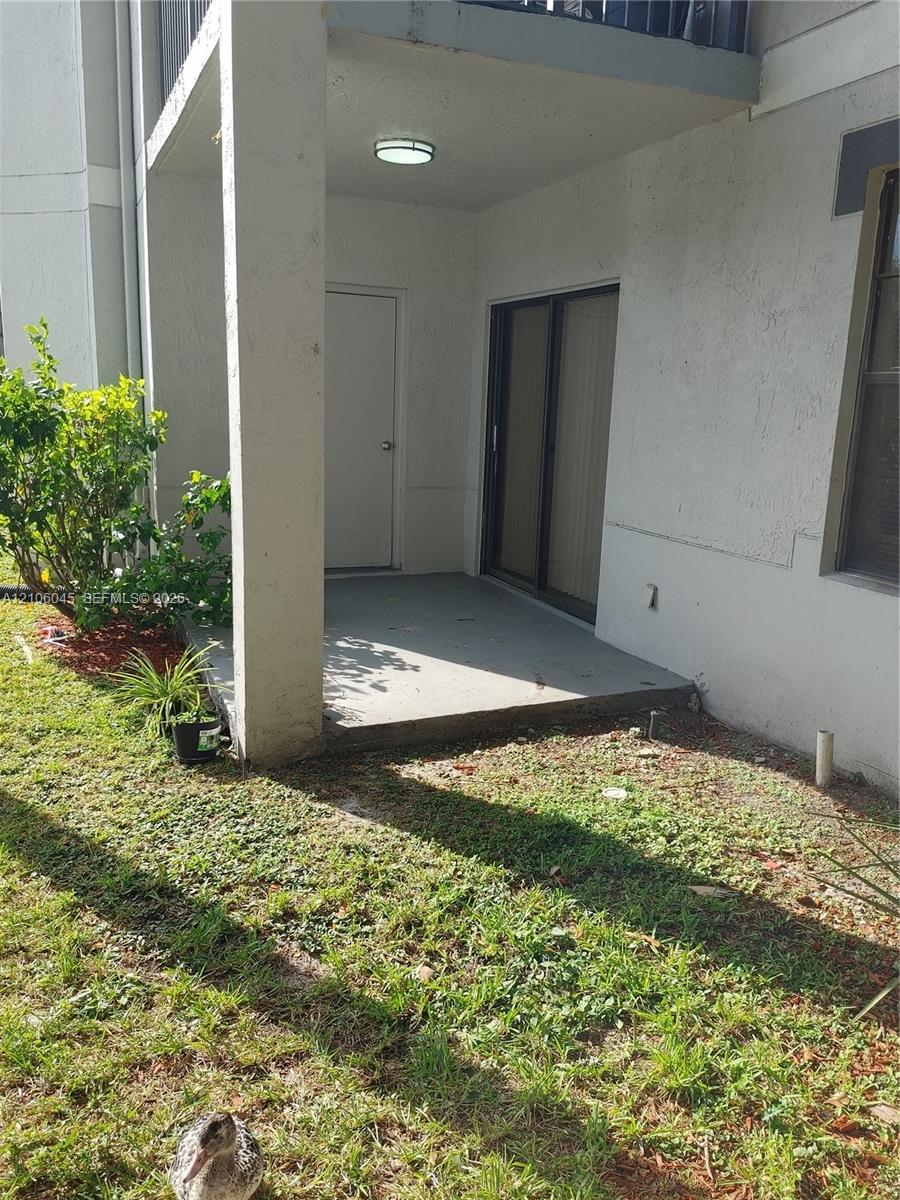 Covered ground-level patio featuring a concrete floor, integrated storage closet, sliding glass door, and overhead lighting