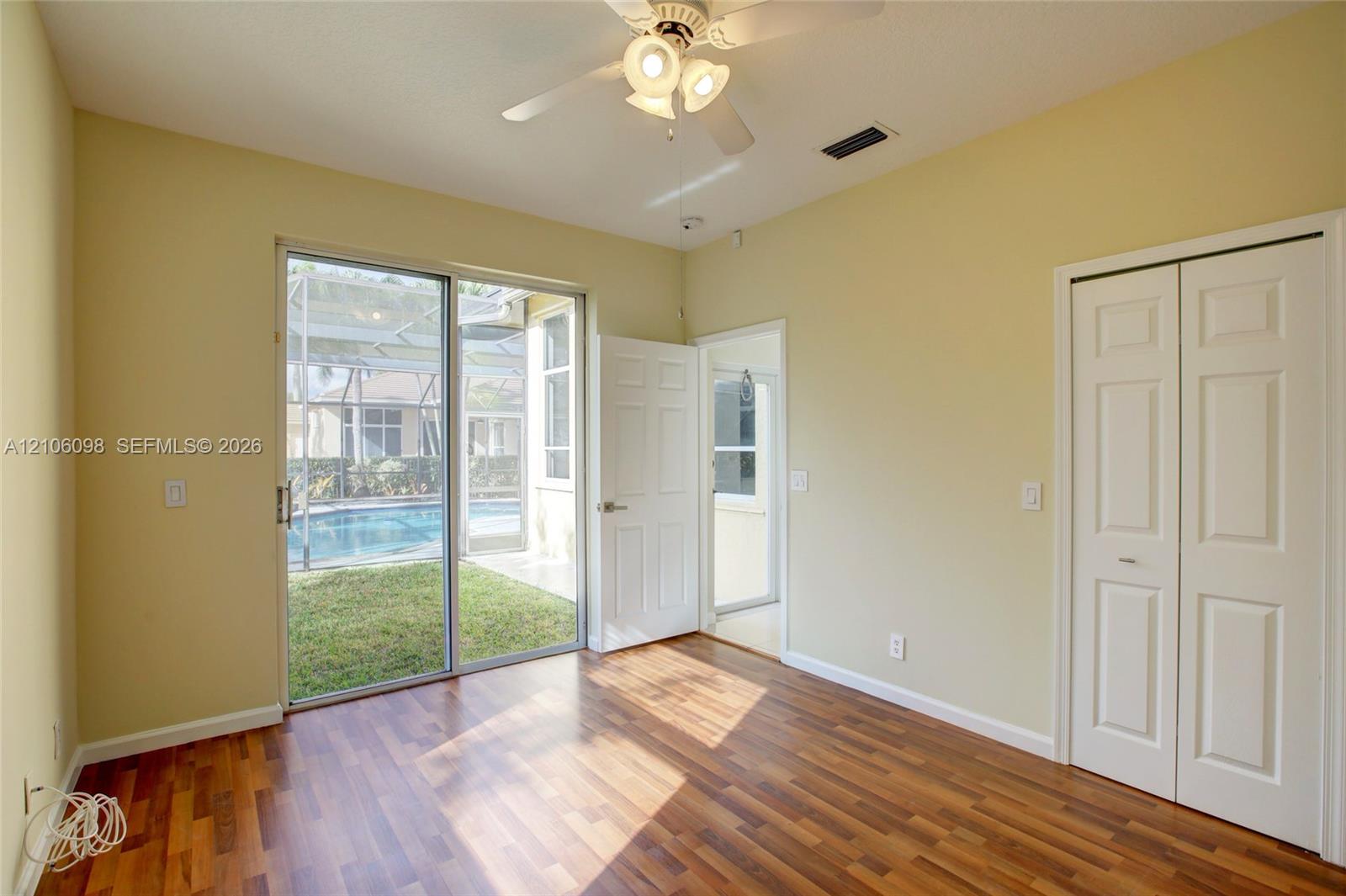 Wood-finish flooring, sliding glass door, ceiling fan with integrated lighting, and white six-panel interior doors