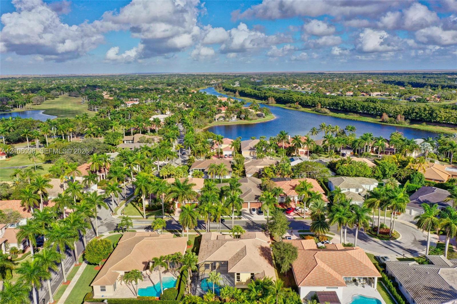 Aerial perspective featuring residential lots with private swimming pools, tile roofing, and mature tropical landscaping within a waterfront community