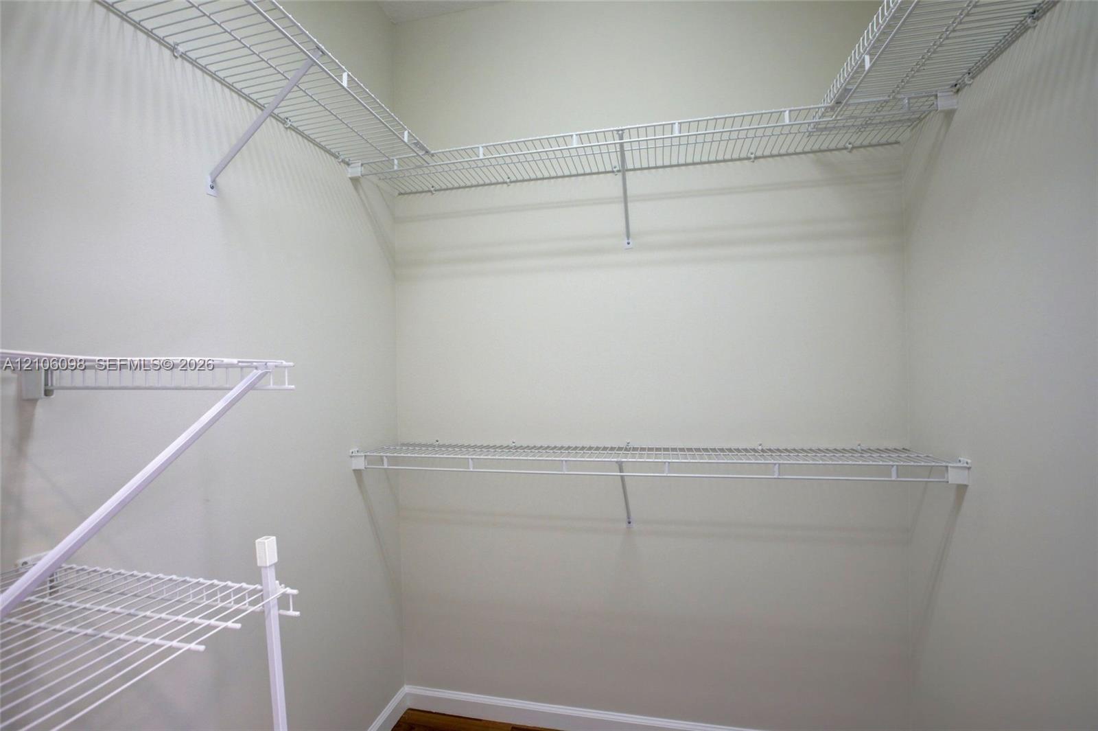 Walk-in storage area featuring multi-level white wire shelving and neutral wall finishes