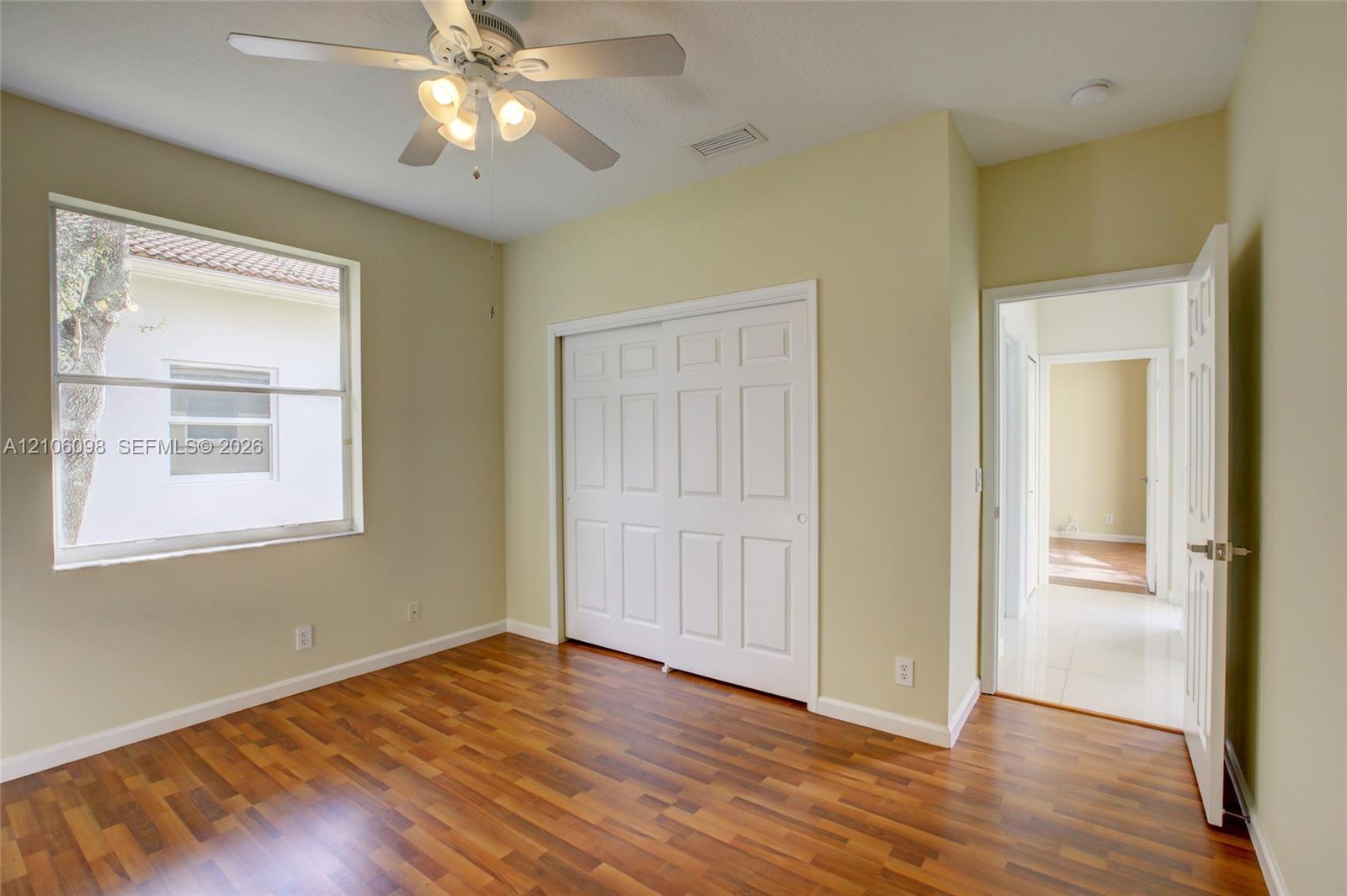 Room featuring wood-finish flooring, a ceiling fan with integrated lighting, a multi-panel closet door, and a single-hung window