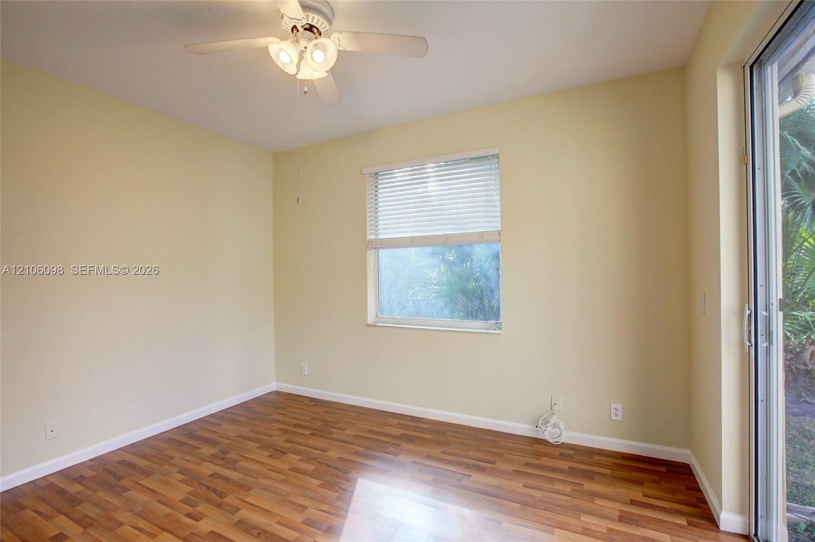 Wood-finish flooring, ceiling fan with integrated lighting, horizontal window blinds, and sliding glass door