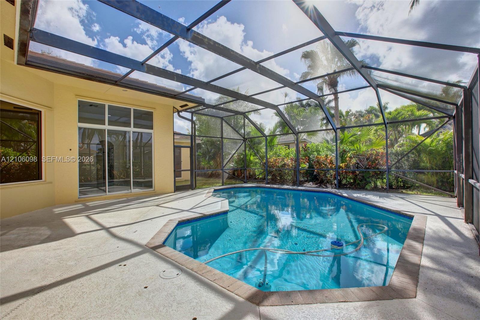 Screened-in patio featuring a concrete pool deck, geometric swimming pool with tiled coping, and large sliding glass doors