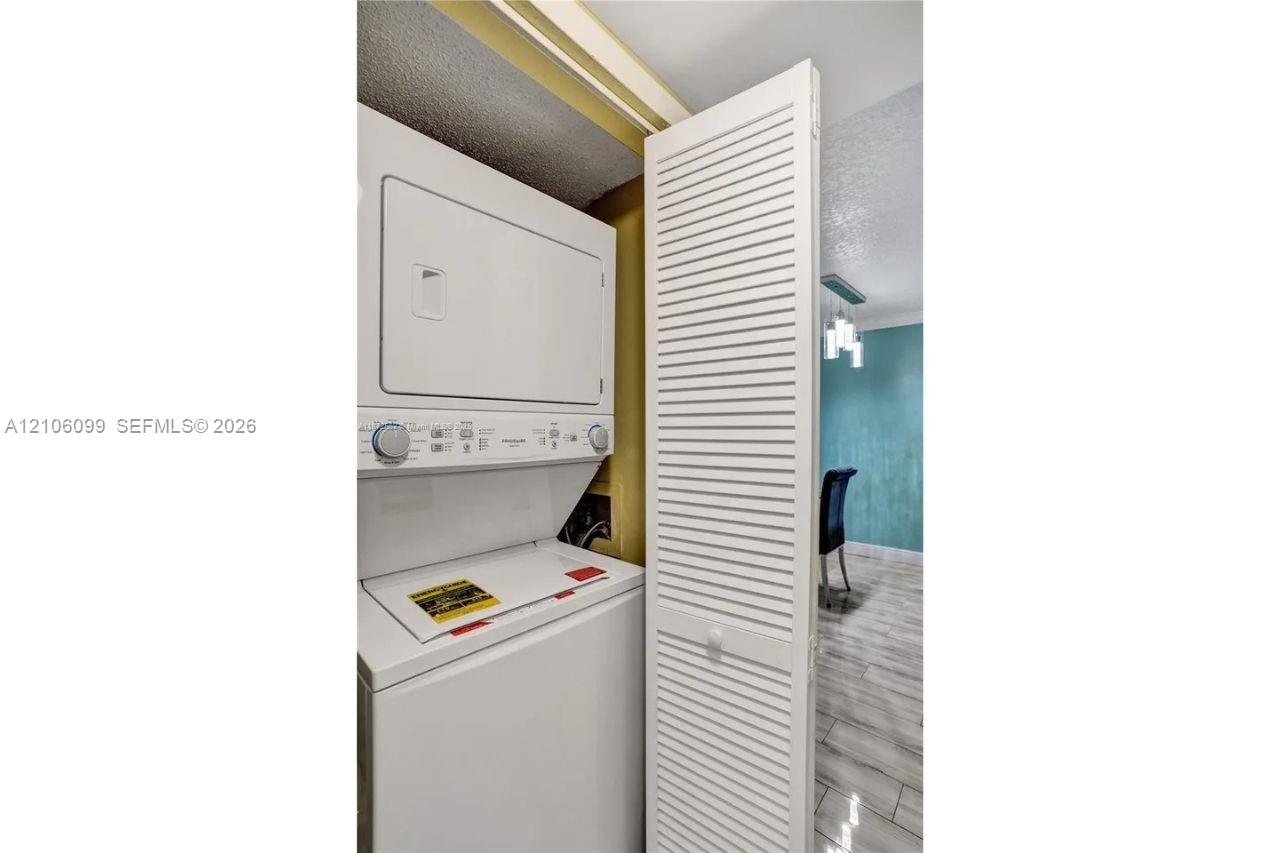 Stackable white laundry unit housed within a closet featuring a white louvered door