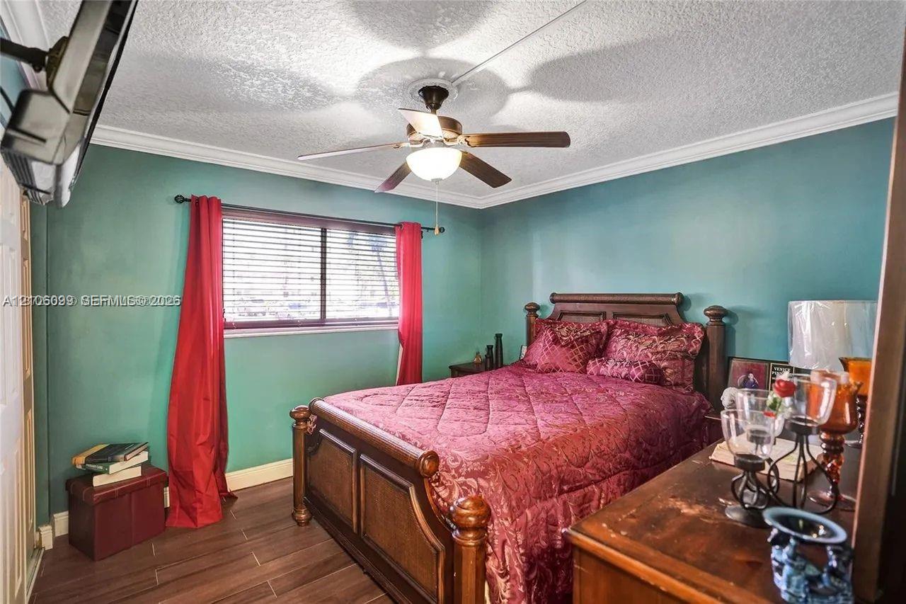 Wood-finish flooring, ceiling fan with integrated lighting, crown molding, and horizontal blind window treatment