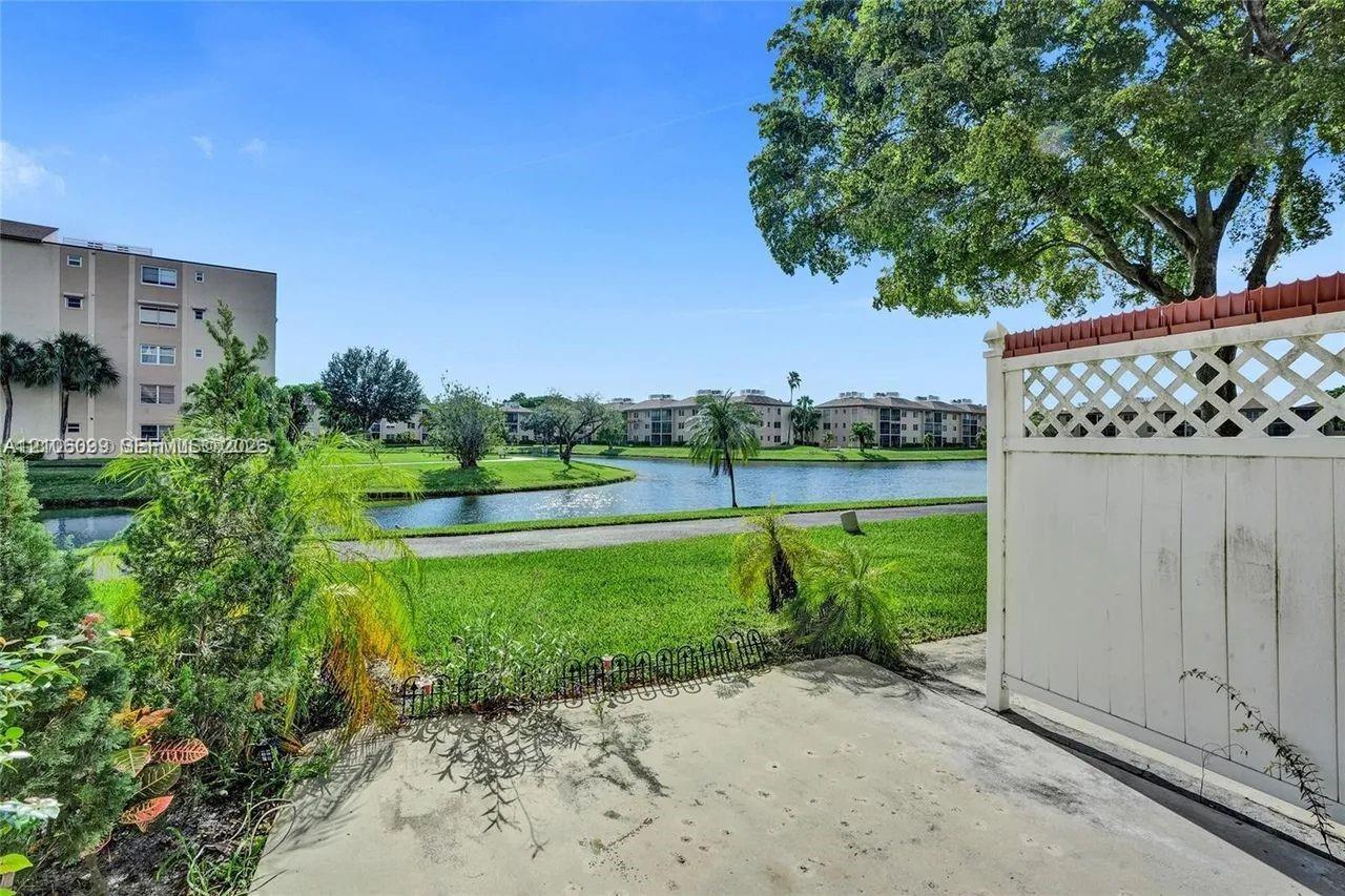 Concrete patio featuring a lattice-topped privacy screen, overlooking a water feature and landscaped grounds