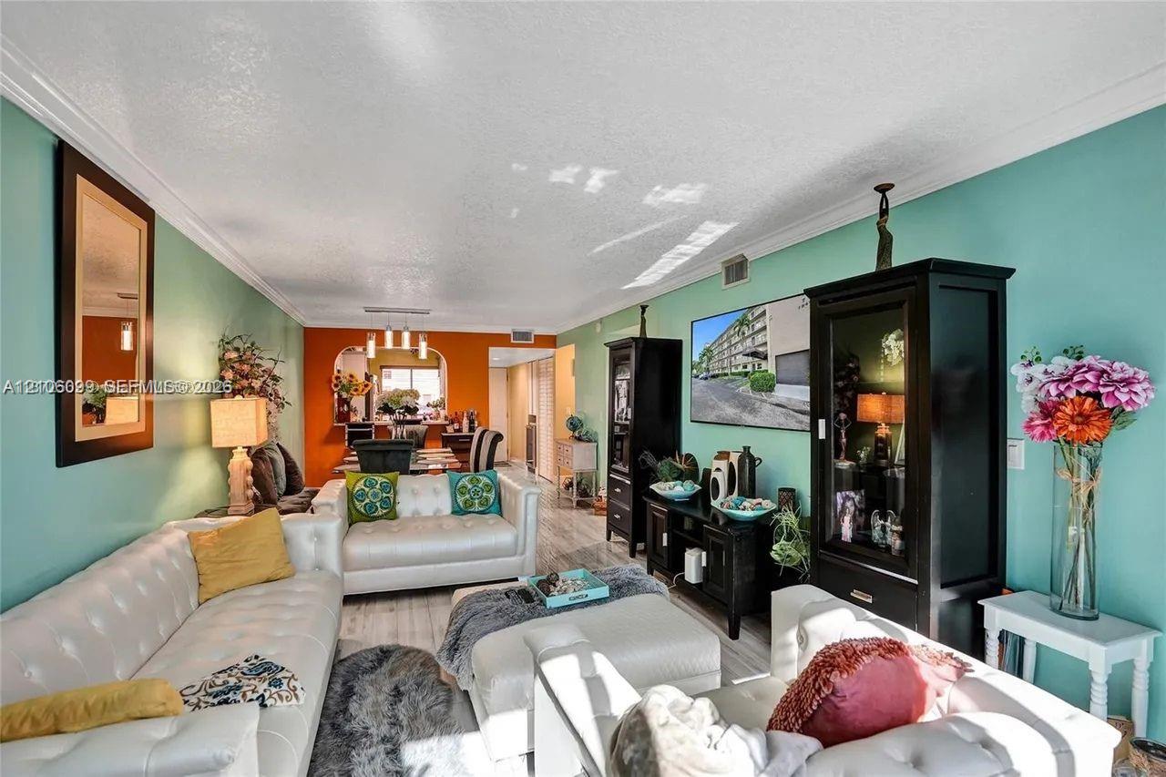 Living area featuring wood-finish flooring, crown molding, and an arched entryway