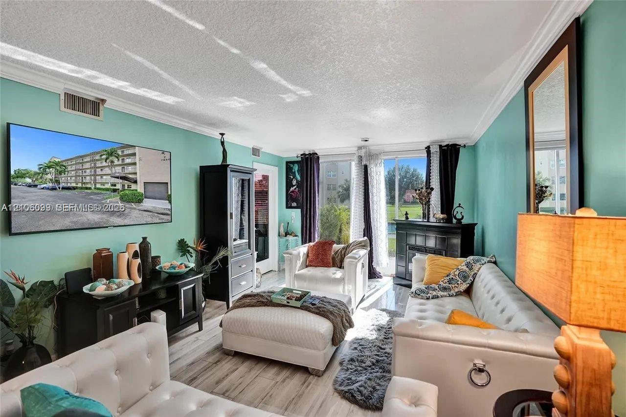 Living area featuring wood-finish flooring, crown molding, and floor-to-ceiling glass sliding doors