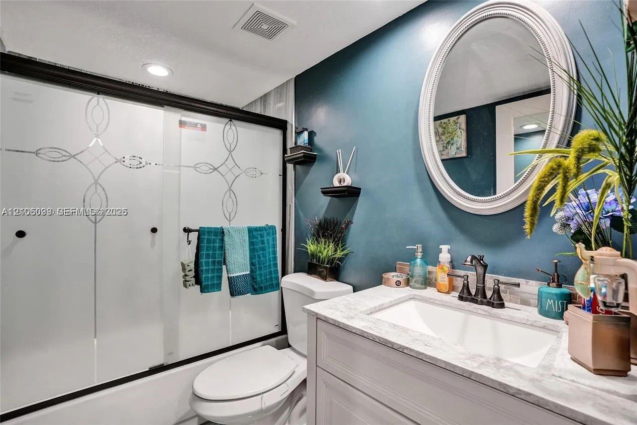 Bathroom featuring a vanity with a light-toned countertop, integrated rectangular basin, and dark-finish widespread faucet