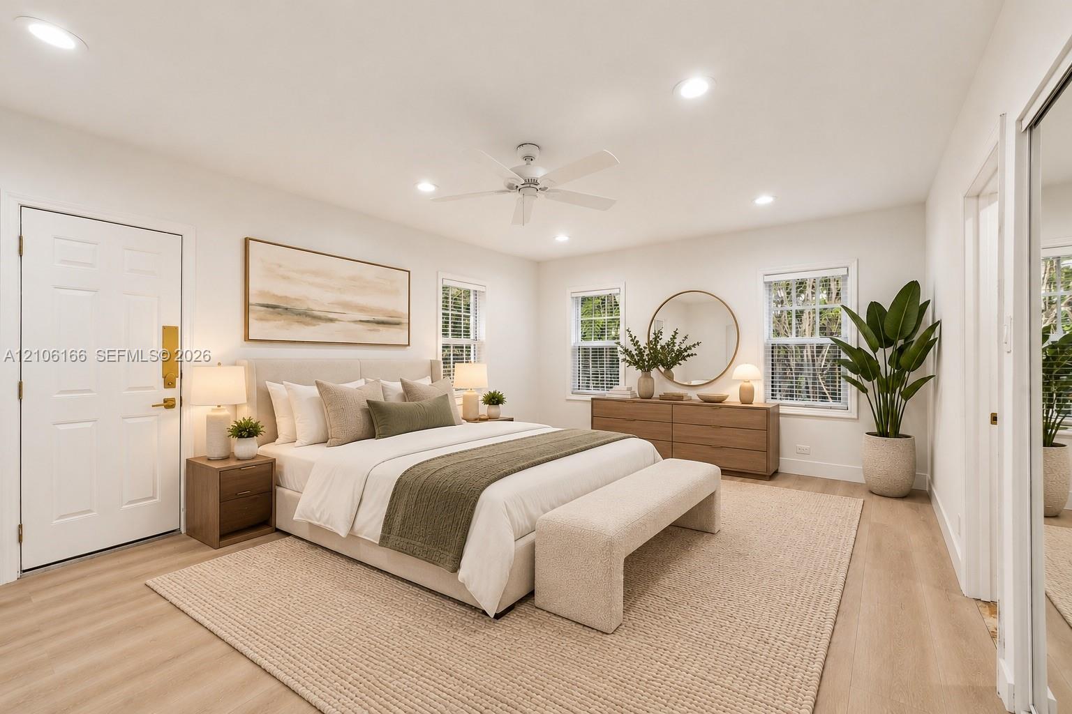 Neutral-toned room featuring wood-finish flooring, recessed lighting, a white ceiling fan, and multiple windows