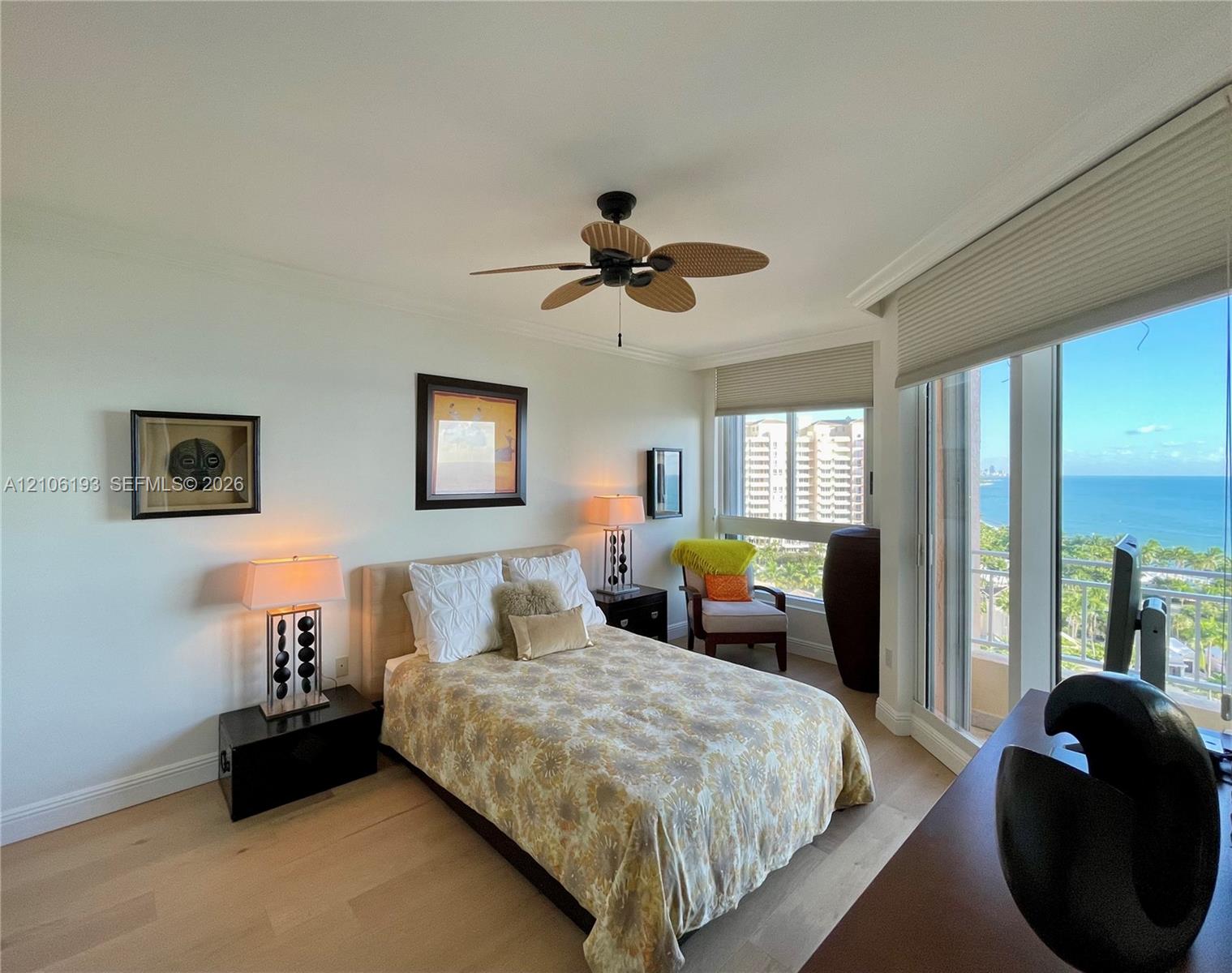 Floor-to-ceiling windows, light wood-finish flooring, ceiling fan, and coastal horizon backdrop