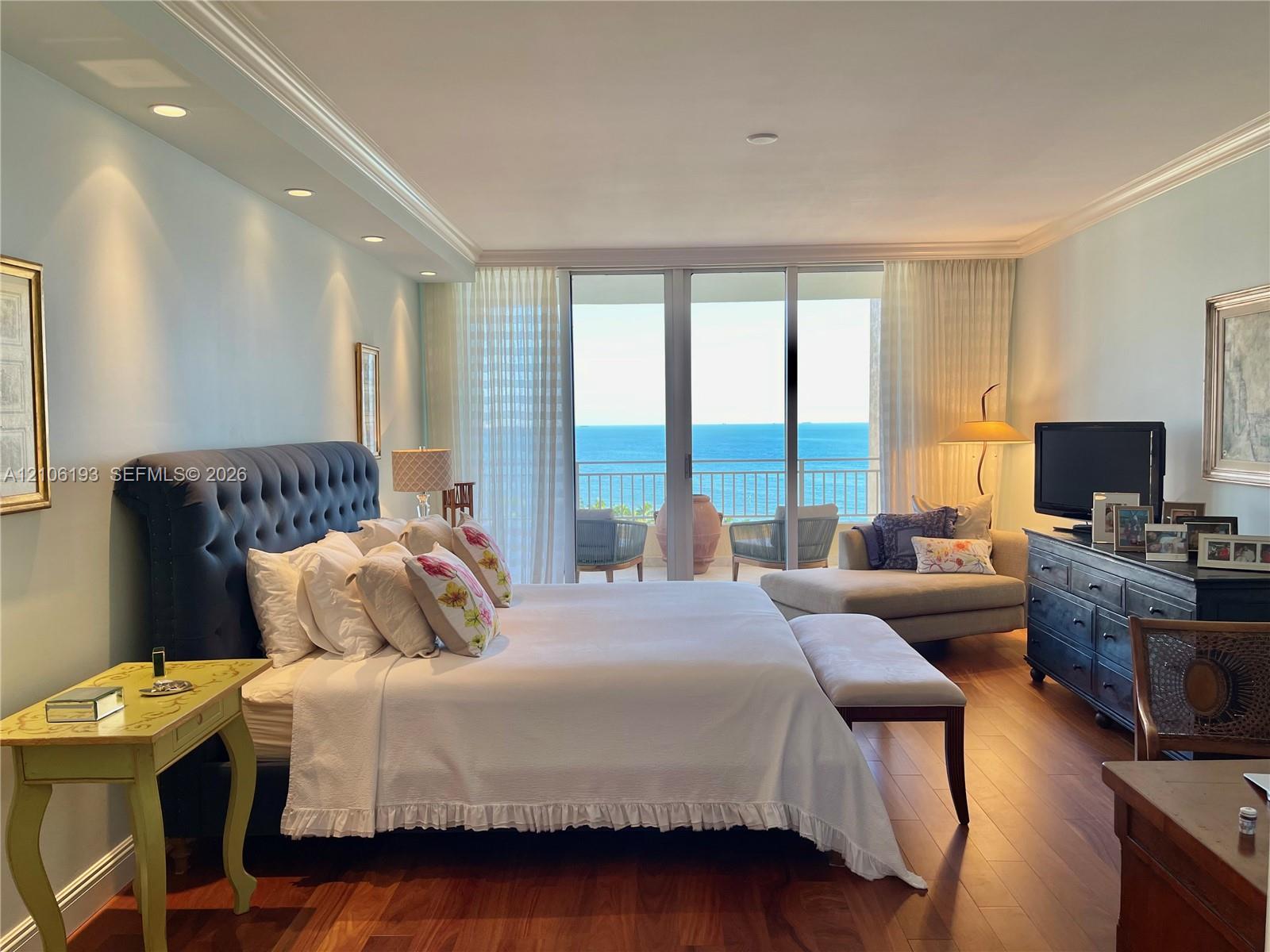 Bedroom featuring wood-finish flooring, recessed lighting, crown molding, and floor-to-ceiling glass sliding doors opening to a balcony with ocean exposure