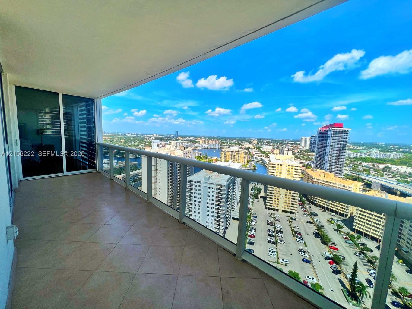 Covered balcony featuring tile flooring and a glass-paneled railing