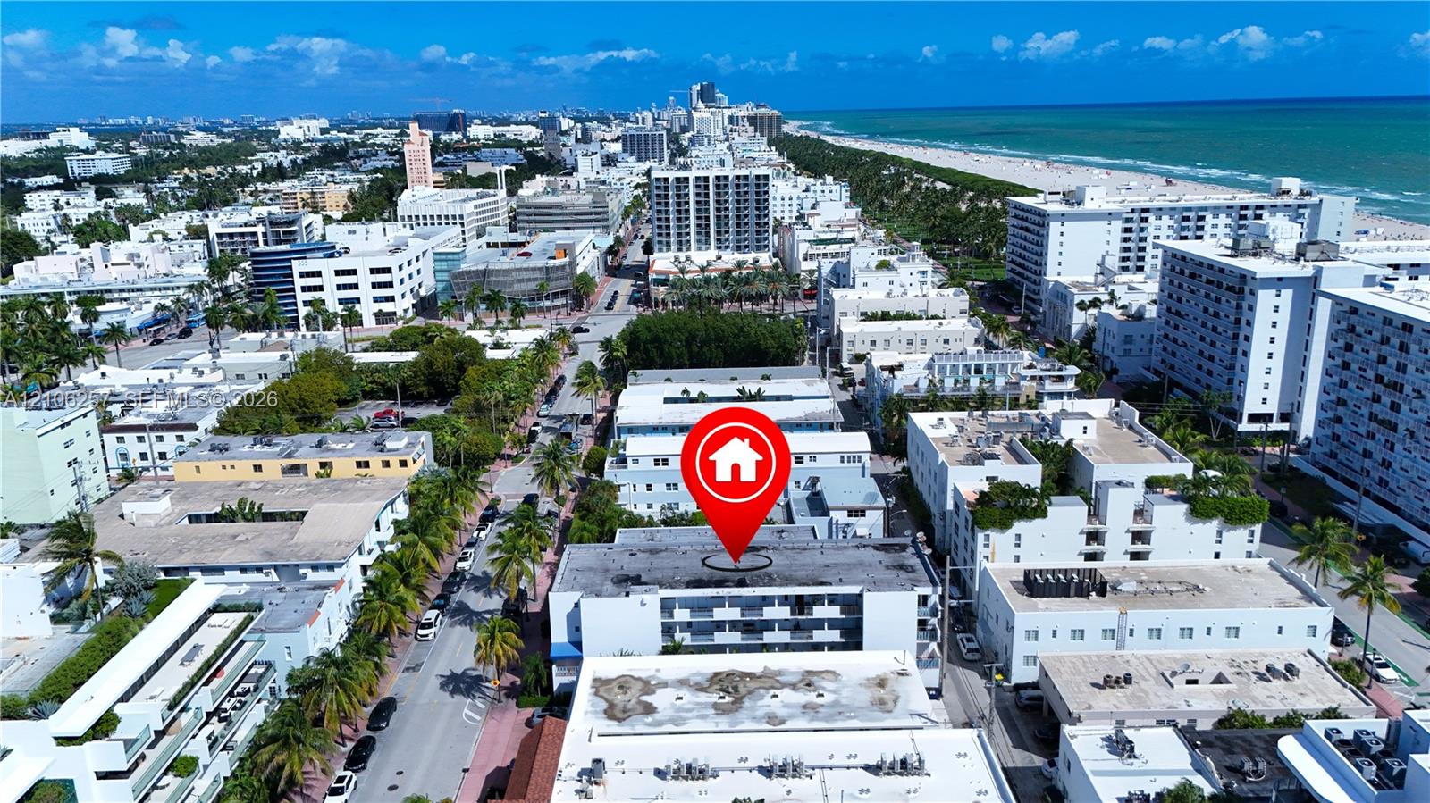 Aerial perspective of a multi-story building featuring tiered balconies, a flat roofline, and urban proximity to the coastline