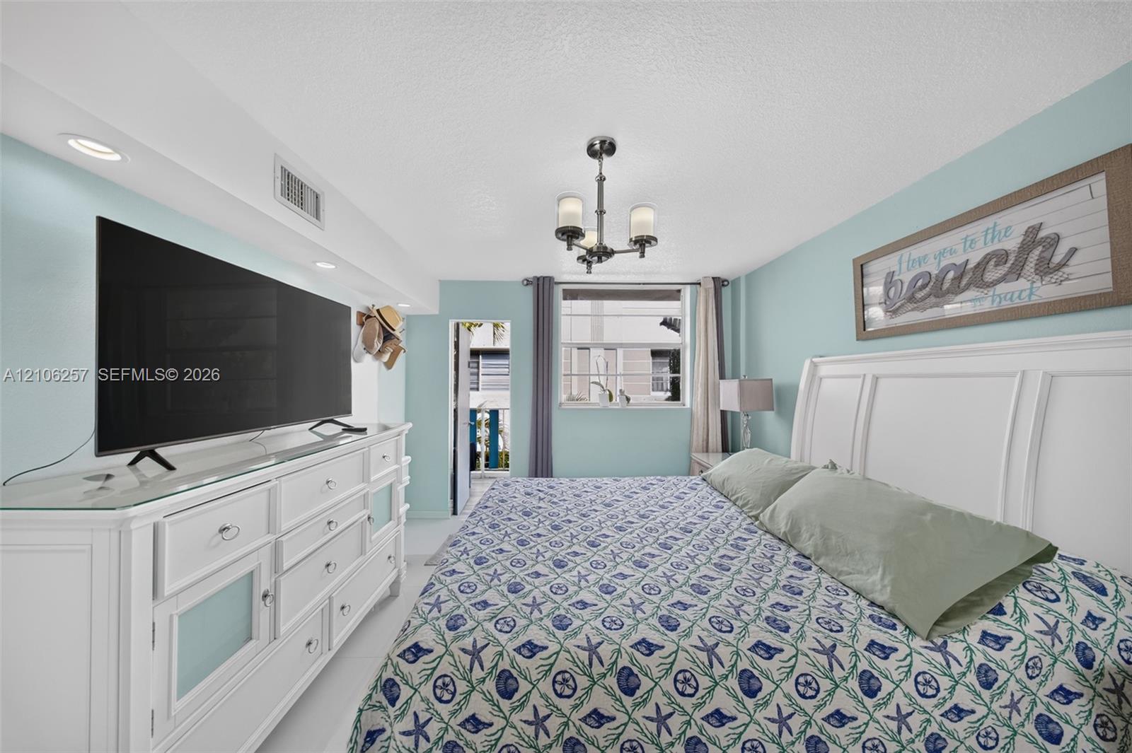 Bedroom featuring recessed accent lighting, a multi-light metal chandelier, and a built-in architectural soffit. Rear balcony off the bedroom.
