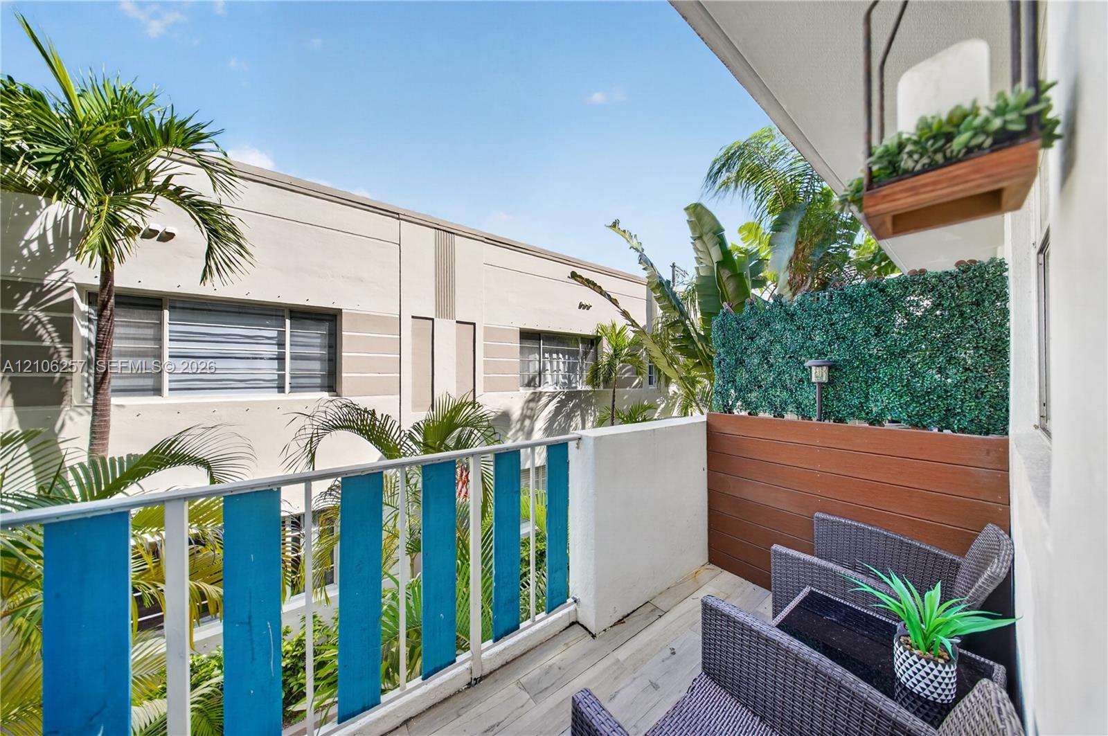 Rear Private balcony featuring wood-finish decking, horizontal wood-plank privacy screening, and metal railing with decorative blue accents