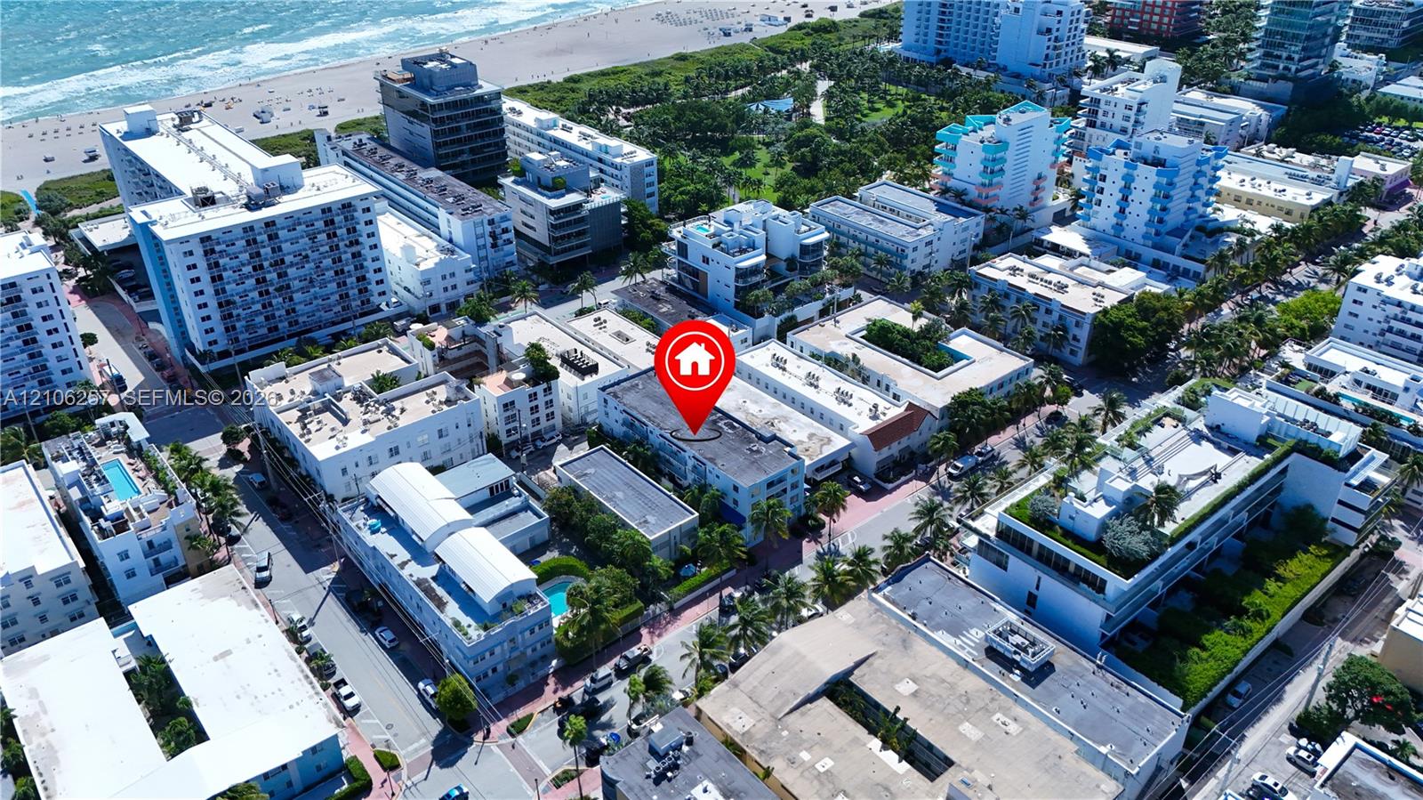 Aerial perspective of a multi-story residential building featuring a flat roof and ground-level landscaping, situated within a coastal urban environment
