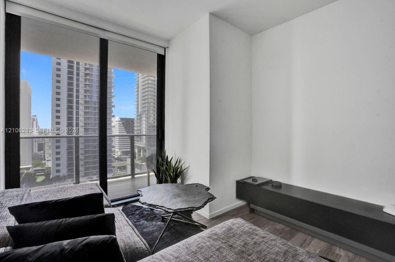 Floor-to-ceiling glass sliding doors, private balcony with metal railing, and wood-finish flooring