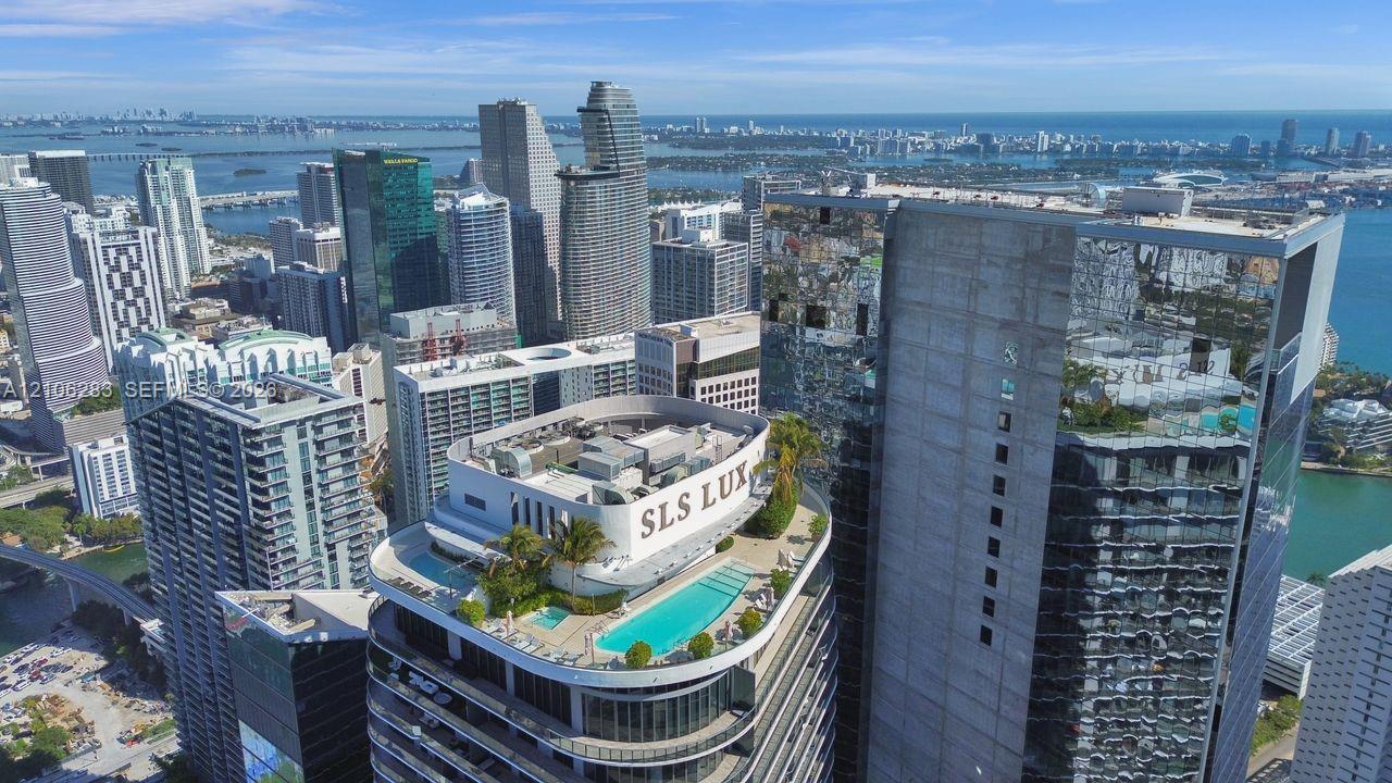 Rooftop swimming pool and spa featuring a concrete terrace, perimeter landscaping, and glass balcony railings