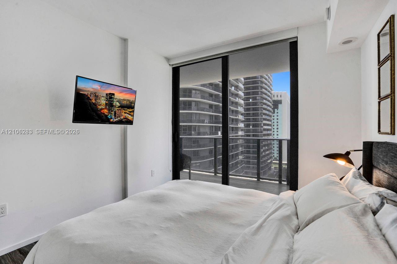 Floor-to-ceiling sliding glass door, private balcony, wood-finish flooring, and recessed ceiling lighting