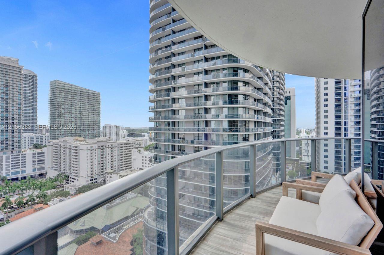 Private balcony with a curved design, glass-paneled railing, and wood-finish flooring