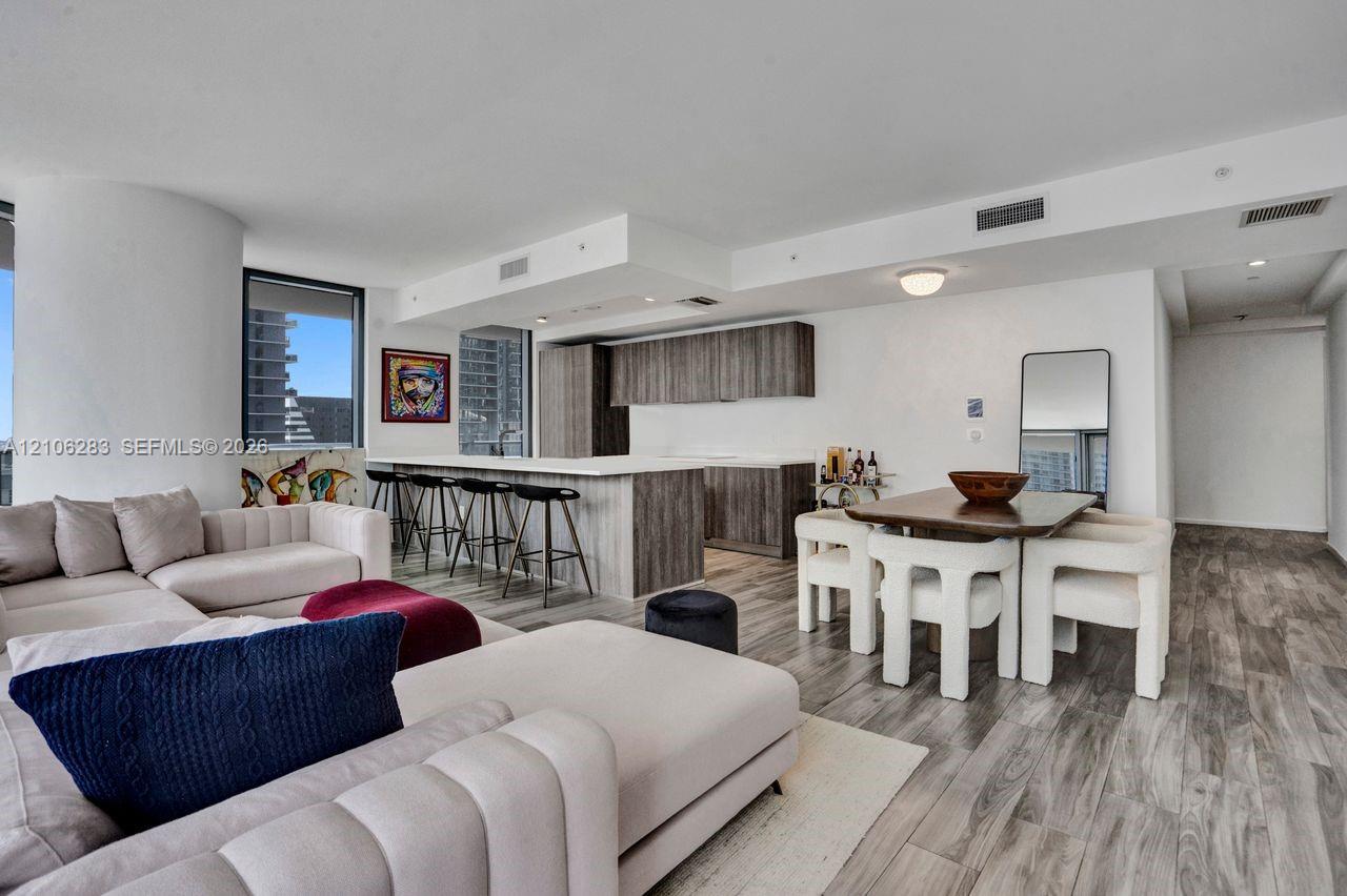Open-concept interior featuring wood-finish flooring, a kitchen island with stone countertop, and custom-finish cabinetry