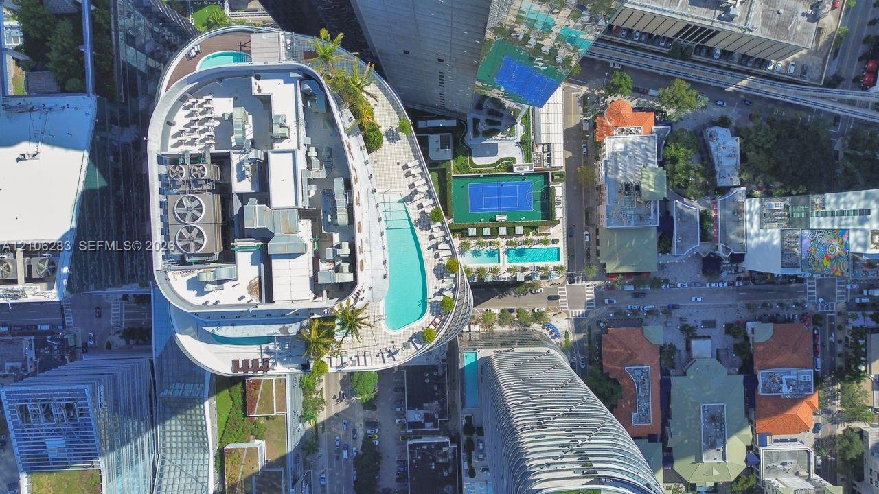 Aerial perspective of building amenities featuring a rooftop swimming pool, landscaped terrace with palm trees, and hardscaped deck areas