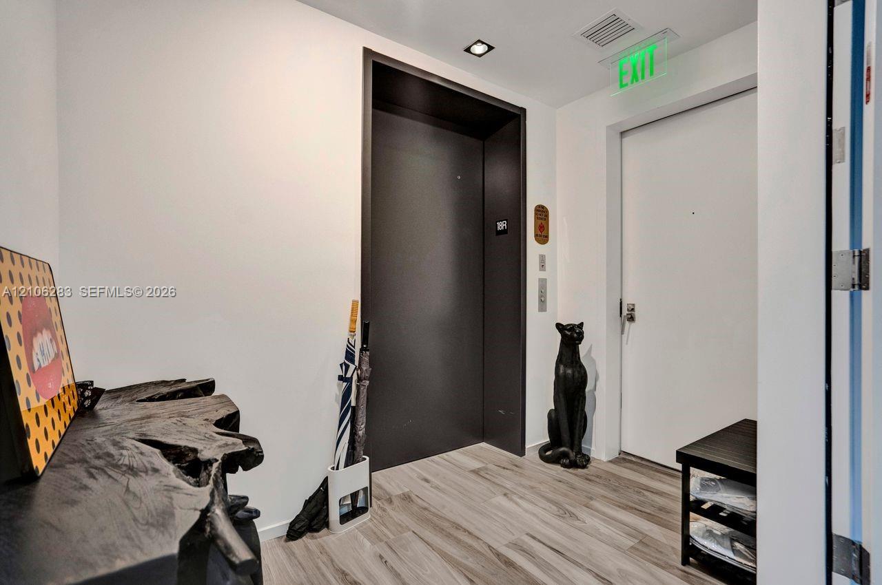 Elevator landing featuring wood-finish flooring, recessed ceiling lighting, and a dark-finished elevator entry