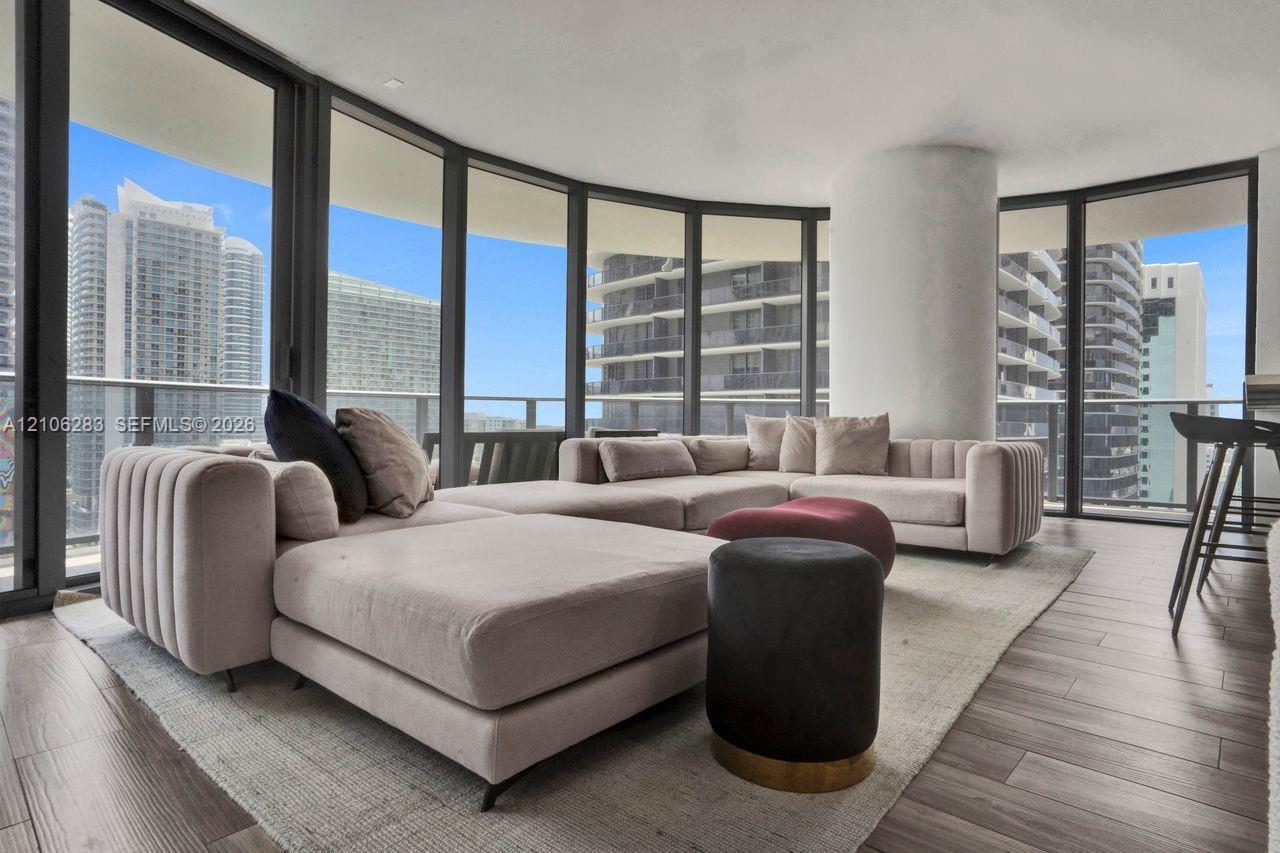 Floor-to-ceiling glass walls, wrap-around balcony access, wood-finish flooring, and structural column
