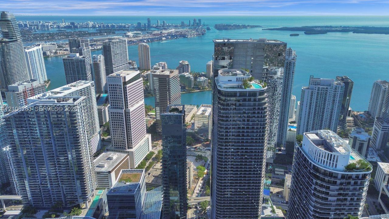 Aerial perspective of a high-rise urban landscape featuring extensive waterfront exposure, dense architectural clusters, and rooftop recreation areas