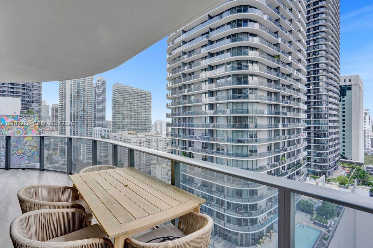 Curved balcony featuring wood-finish flooring and metal railings, overlooking an urban skyline