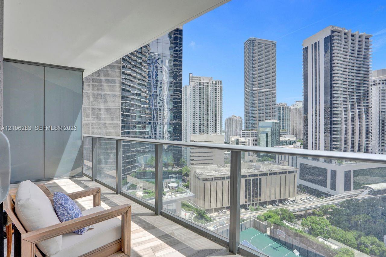 Covered private balcony featuring tile flooring and a glass panel railing with a panoramic cityscape backdrop