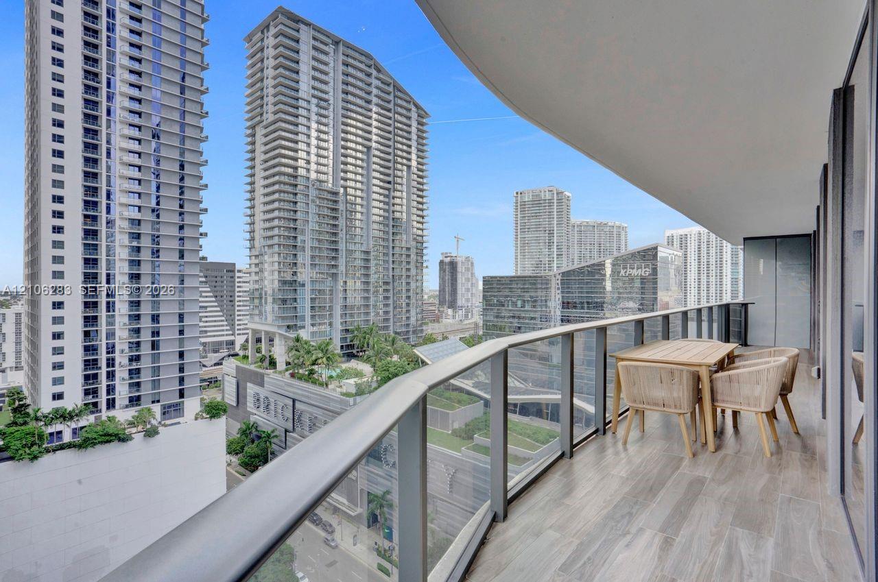 Covered balcony featuring wood-finish flooring and a glass-paneled metal railing
