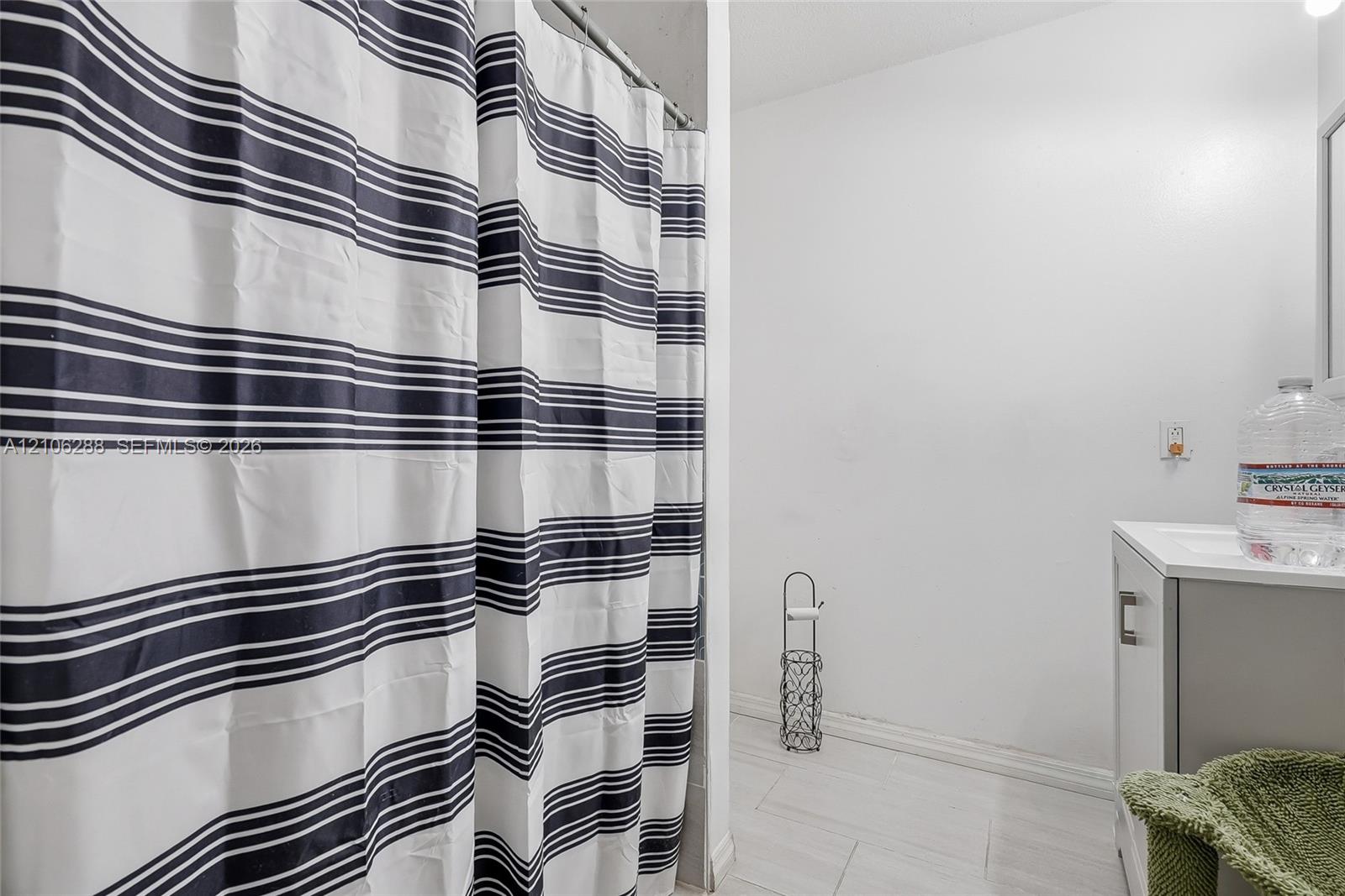 Bathroom featuring light-toned tile flooring and a white vanity with a rectangular sink