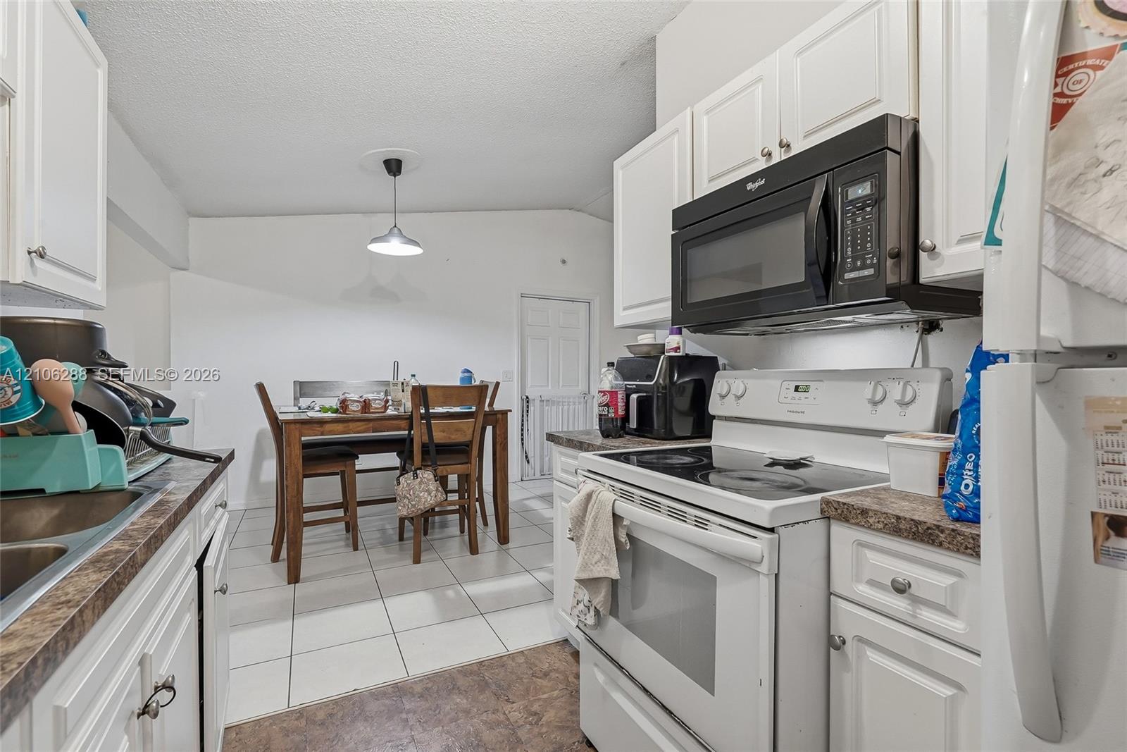 Kitchen featuring white cabinetry, stone-finish countertops, stainless steel electric range, over-the-range microwave, and tile flooring