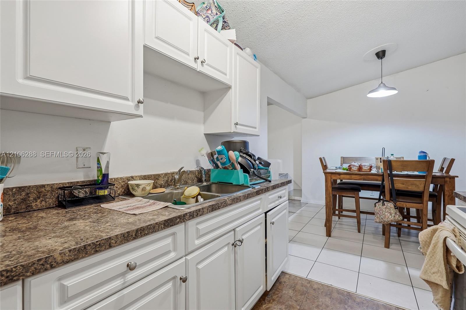 Kitchen featuring white shaker-style cabinetry, a dual-basin stainless steel sink, and a high-contrast laminate countertop