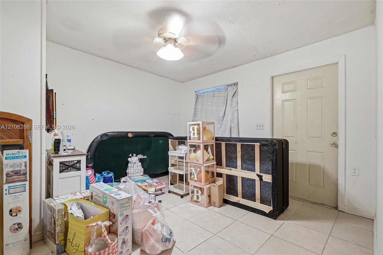 Room featuring tile flooring, ceiling fan, and a six-panel entry door