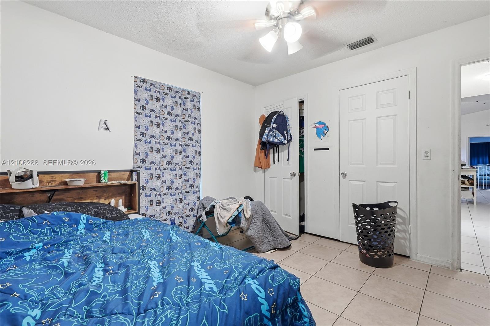 Neutral-tone tile flooring, multi-panel interior doors, and a ceiling-mounted light fixture with a fan