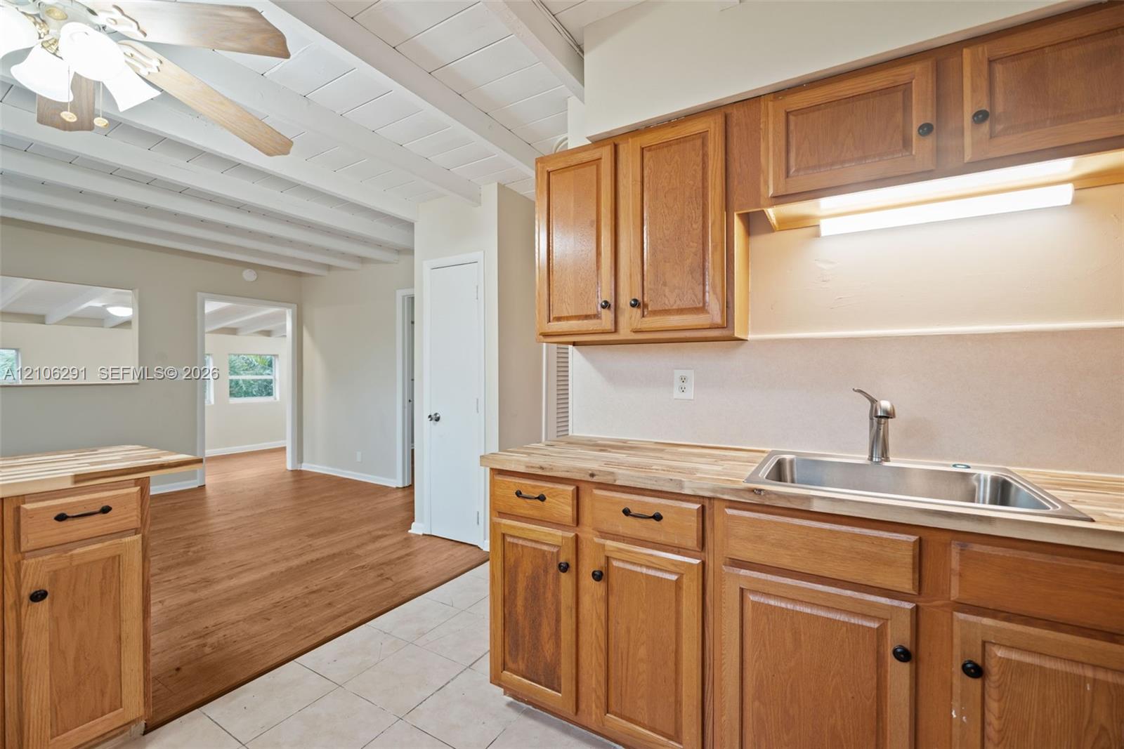 Kitchen featuring butcher block countertops, stainless steel sink, wood cabinetry, and vaulted ceilings with exposed beams