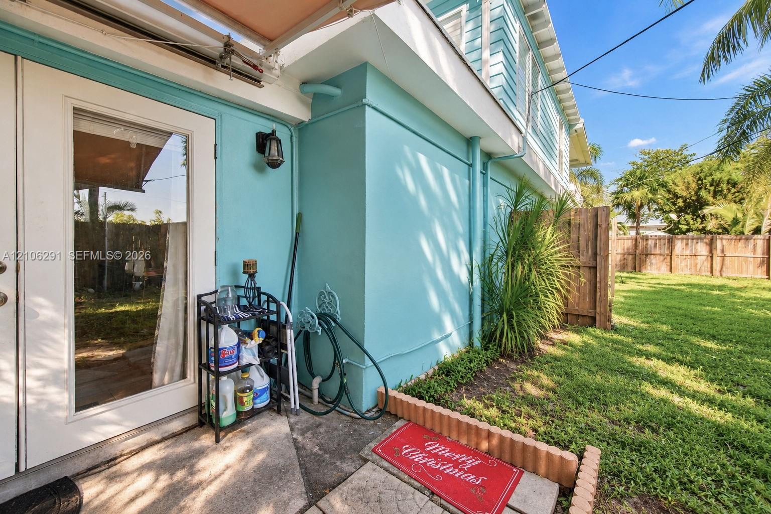 Exterior view featuring painted stucco siding, glass-paned double doors, exterior sconce lighting, and a fenced backyard with lawn