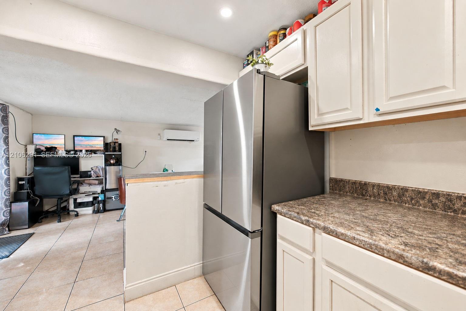 Kitchen featuring white cabinetry, stone-finish countertops, stainless steel refrigerator, and tiled flooring