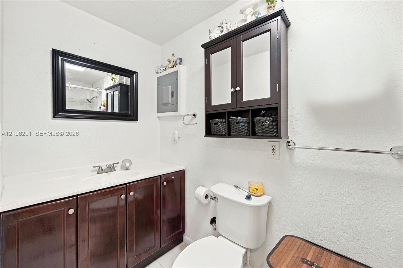 Dark wood-finish vanity with integrated countertop, wall-mounted mirrored medicine cabinet, and framed wall mirror