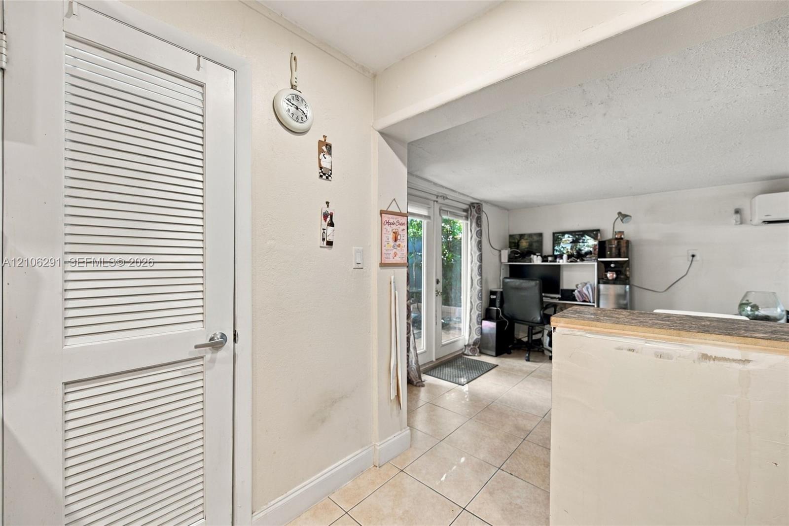Interior featuring tiled flooring, a louvered-panel door, and glass-paned double doors with exterior exposure