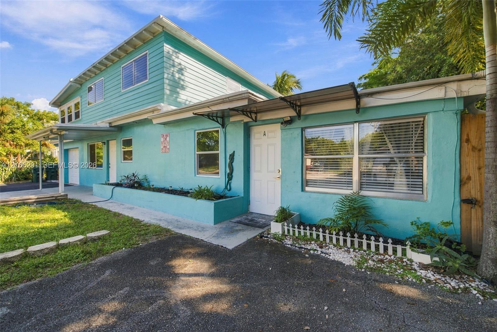 Two-story residence featuring horizontal lap siding, a built-in elevated concrete planter box, dual metal awnings, and an asphalt-paved driveway