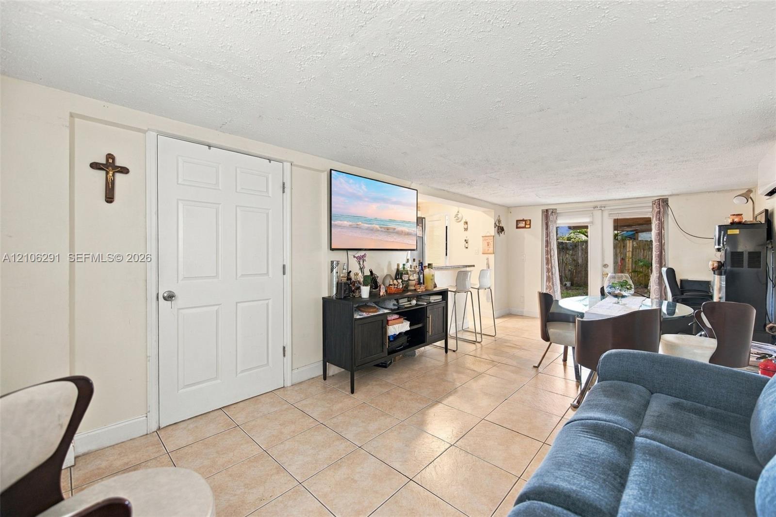 Living area featuring large-format ceramic tile flooring, a recessed pass-through window with an integrated breakfast bar, and glass-paned sliding doors